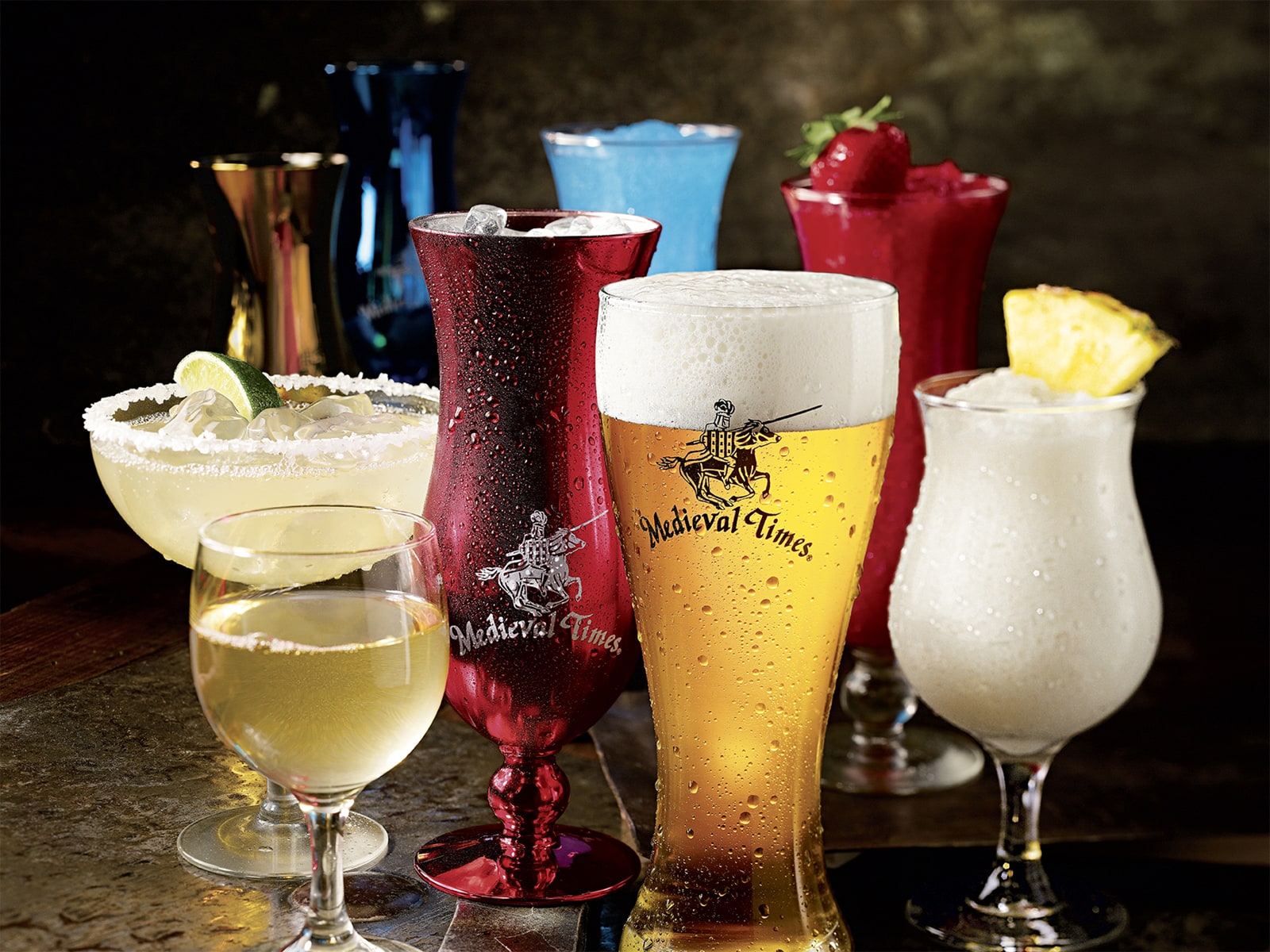 A vibrant grouping of specialty drinks, including wine, beer, and colorful margaritas, sit on a bar top.