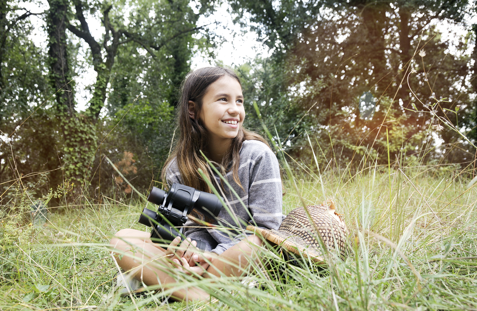 Girl Scout sitting in a field with binoculars